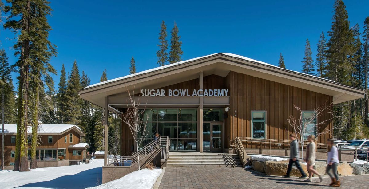 The Sugar Bowl Academy building in winter, surrounded by snow and Sierra pines.